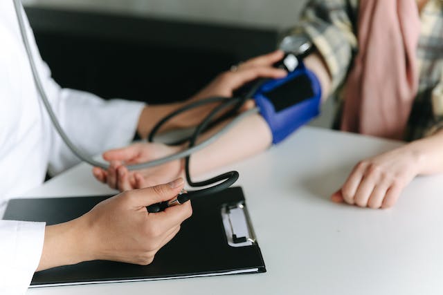 A physician taking the blood pressure of a female patient