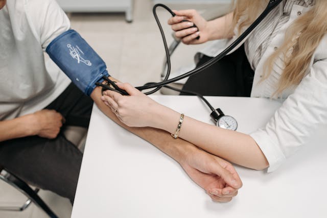 An upper arm blood pressure monitor is being used to take the reading