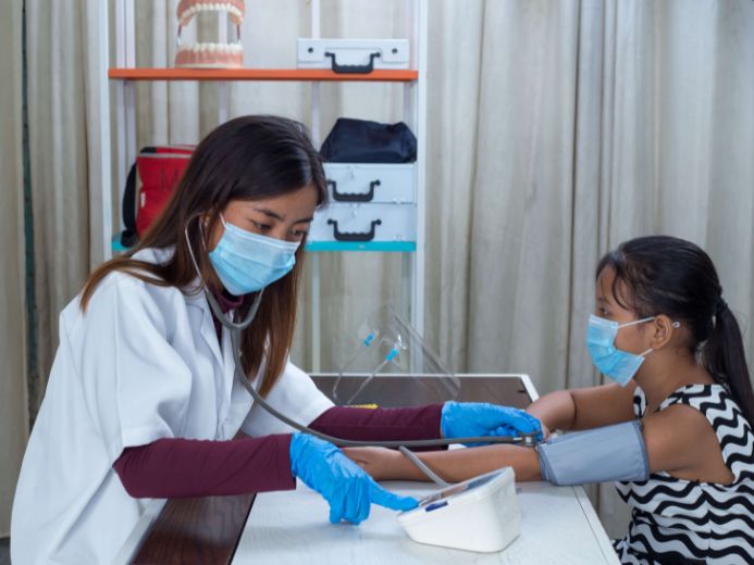 Healthcare professionals monitoring a young patient's blood pressure in a medical office using pediatric blood pressure monitors