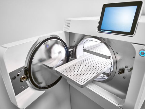 An automated autoclave sterilizer is ready for a sterilization cycle with its clean accessories