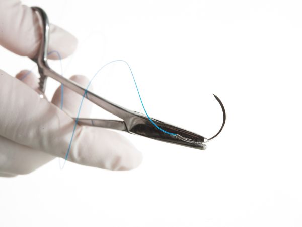 A suture is attached to a needle which is held by a needle holder