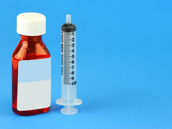 A child’s medicine is mixed into sweetened water before administration with an oral syringe