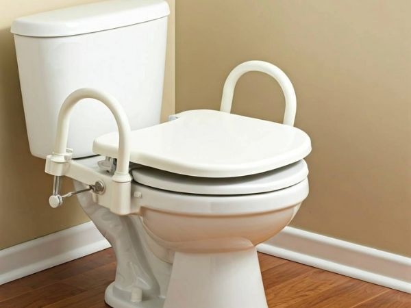 A raised toilet seat with arms is attached to the standard toilet seat